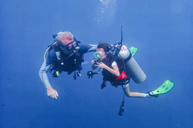 SSI Tauchlehrer bildet Tauchschüler unter Wasser in blauen Gewässern von Tulamben, Bali aus