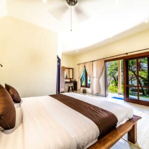 Bright bungalow bedroom with king bed and garden view at Ocean Sun Dive Resort in Tulamben