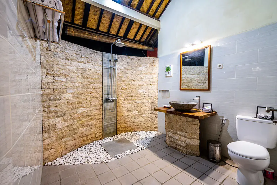 Luxury bathroom at Ocean Sun Dive Resort Tulamben with natural stone walls and open shower