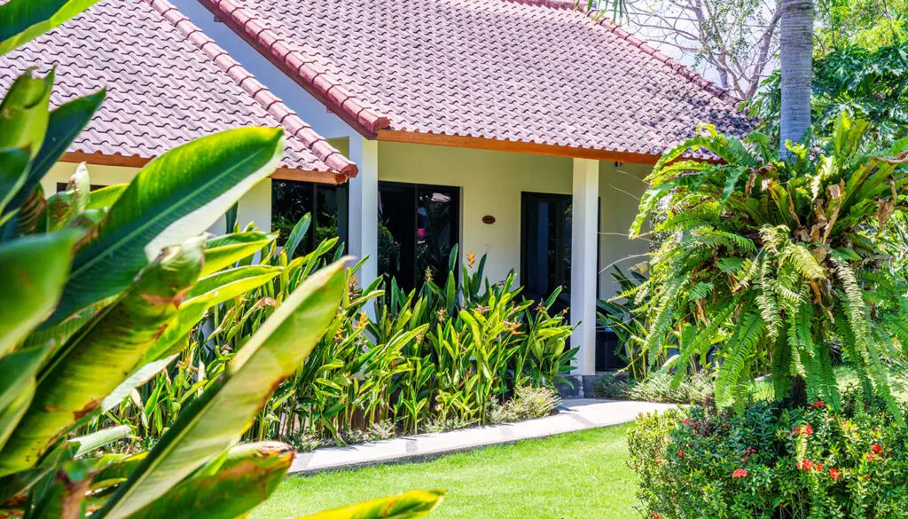 Traditional Balinese bungalow with terracotta roof surrounded by tropical garden at Ocean Sun Dive Resort Tulamben