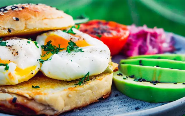 Gourmet breakfast with poached egg on toasted bread, avocado slices and tomato at Ocean Sun Dive Resort Tulamben